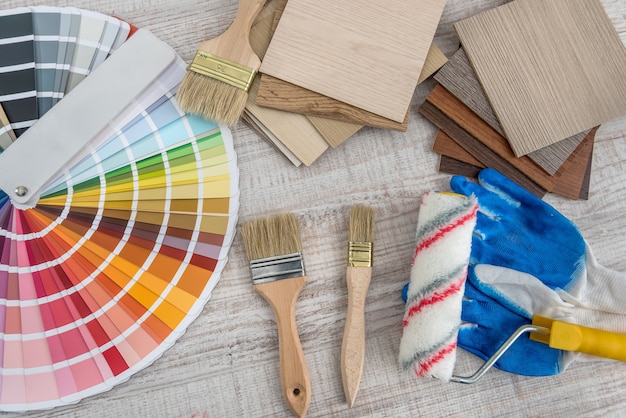 Gants de protection bleus avec palette de couleurs et pinceaux pour la réparation ou la rénovation de la maison sur planche de bois