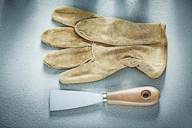 Gants de protection en cuir de couteau à mastic sur le concept de construction de fond en béton