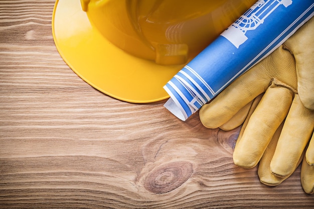 Gants de sécurité de casque de construction de plan laminé bleu sur le concept de construction de planche de bois