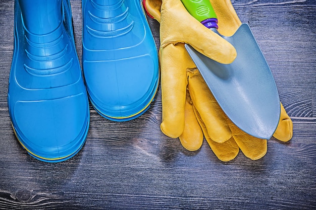 Gants de sécurité en cuir bêche à main en métal bottes en caoutchouc imperméables sur planche de bois concept d'agriculture