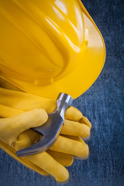 Gants de sécurité en cuir casque de construction et marteau à griffes sur le concept de construction de surface métallique rayée