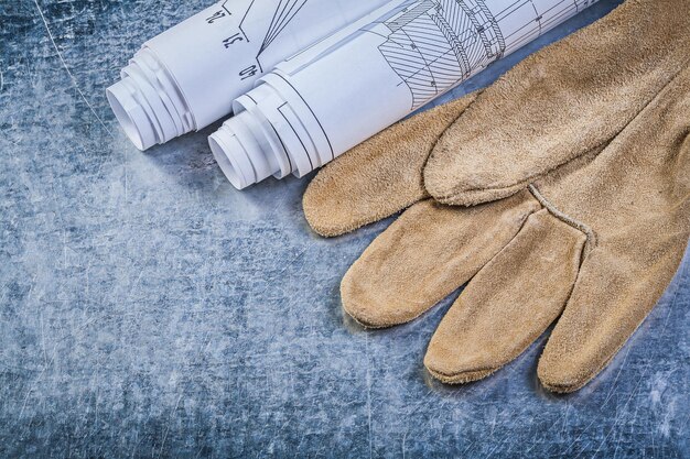 Gants de sécurité en cuir de dessins d'ingénierie roulés sur le concept de construction de fond métallique.