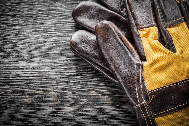 Gants de sécurité en cuir sur planche de bois.