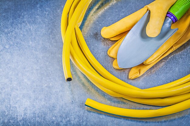 Gants de sécurité pour tuyau d'arrosage en caoutchouc bêche à main sur fond métallique concept de jardinage