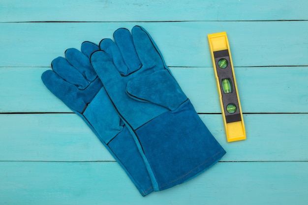 Gants de travail, niveau sur fond de bois bleu. Vue de dessus