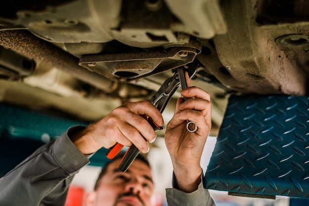 Garagiste travaillant sur une voiture levée.