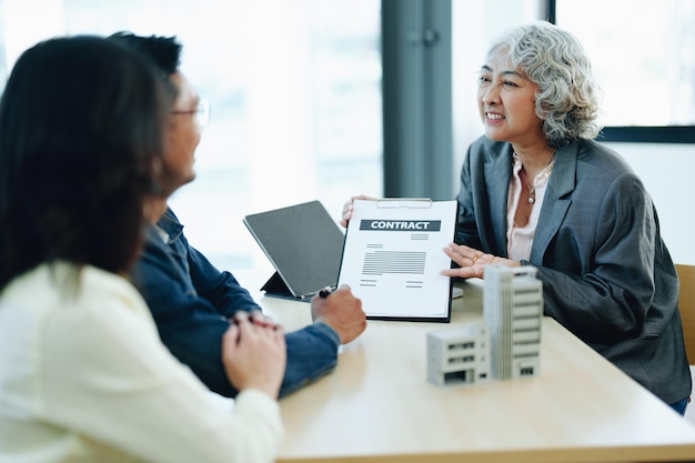 Garantie Assurance Signer un contrat couple un couple souriant signe un contrat pour investir dans l'immobilier avec l'agent hypothécaire avec la banque