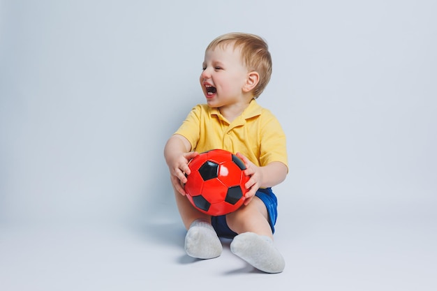 Garçon de 34 ans fan de football dans un t-shirt jaune avec un ballon dans ses mains tenant un ballon de football dans ses mains isolé sur fond blanc Le concept de loisirs sportifs en famille