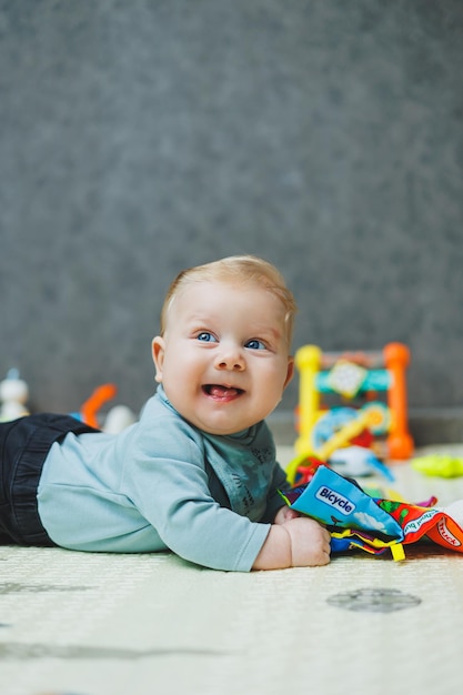 Un garçon de 4 mois est allongé sur un tapis et rampent Le bébé est allongée sur un tapas thermique et joue Autodéveloppement d'un nouveau-né Jouets pour le développement de l'enfant