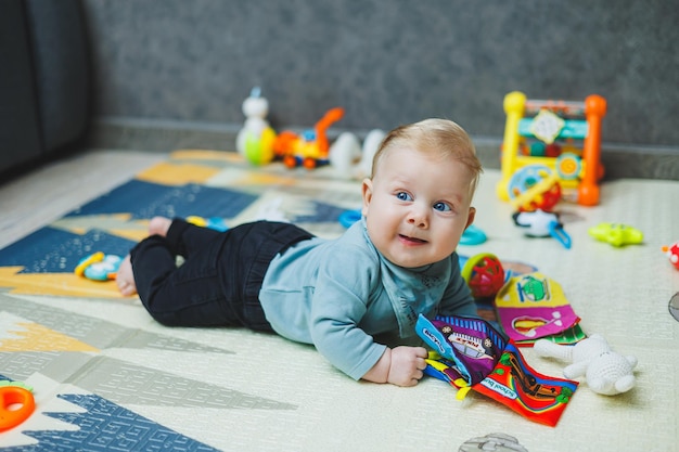 Un garçon de 4 mois est allongé sur un tapis et rampent Le bébé est allongée sur un tapas thermique et joue Autodéveloppement d'un nouveau-né Jouets pour le développement de l'enfant