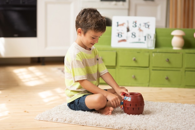 Un garçon de 7 ans s'assoit sur le tapis et joue avec des jouets à la maison Jeux éducatifs