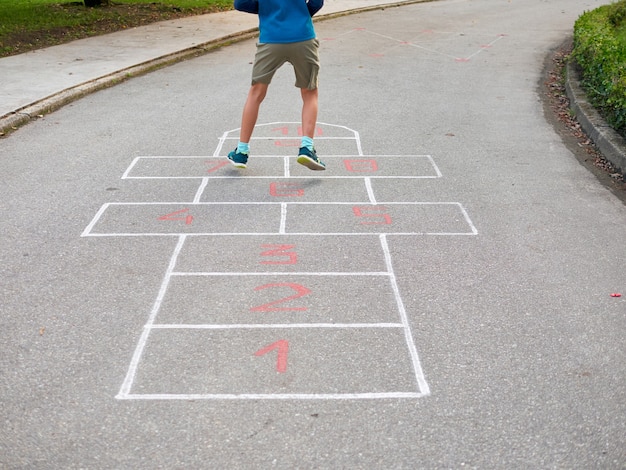 Garçon de 8 ans jouant à la marelle, vue arrière