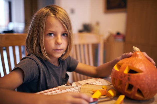 Garçon de 8 ans sculptant la citrouille d'Halloween