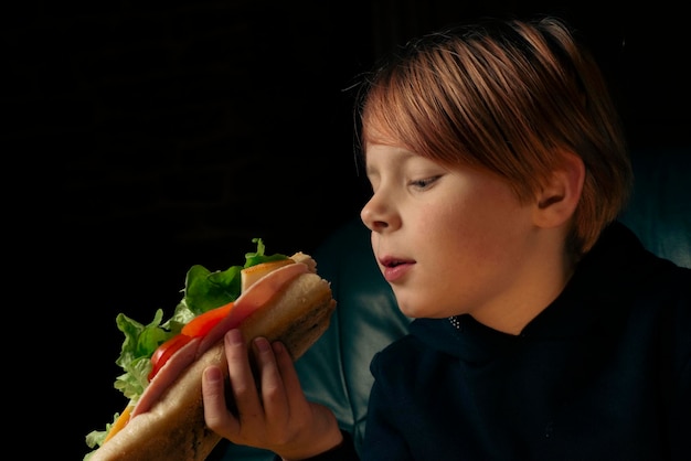 Garçon de 9 ans mangeant un gros sandwich baguette