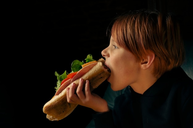 Garçon de 9 ans mangeant un gros sandwich baguette