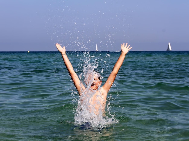 Garçon actif jouant avec de l'eau de mer.