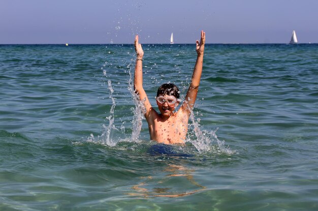 Garçon actif jouant avec de l'eau de mer.