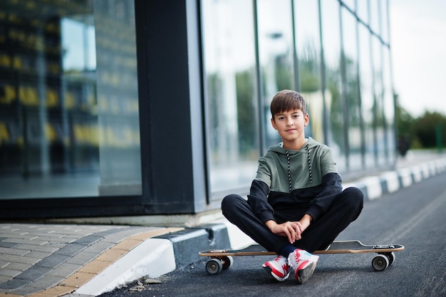 Garçon adolescent dans un costume de sport avec longboard