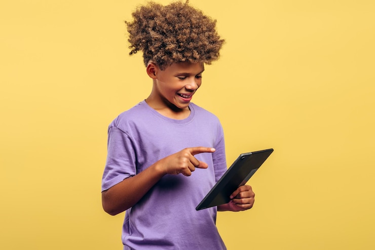 Photo un garçon afro-américain attrayant souriant aux cheveux bouclés tenant une tablette numérique à l'aide d'une application mobile