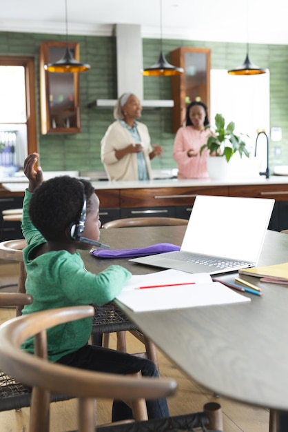 Photo un garçon afro-américain ayant un cours en ligne en utilisant des écouteurs et un ordinateur portable avec un espace de copie au ralenti