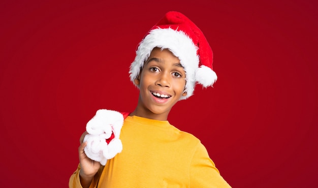 Garçon afro-américain avec un chapeau de Noël sur fond rouge