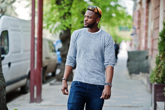 Garçon afro-américain élégant sur pull gris et lunettes de soleil noires posées dans la rue