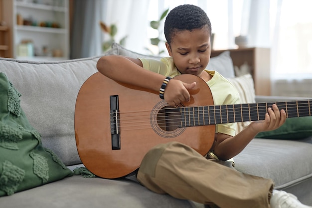 Un garçon afro-américain joue de la guitare à la maison.