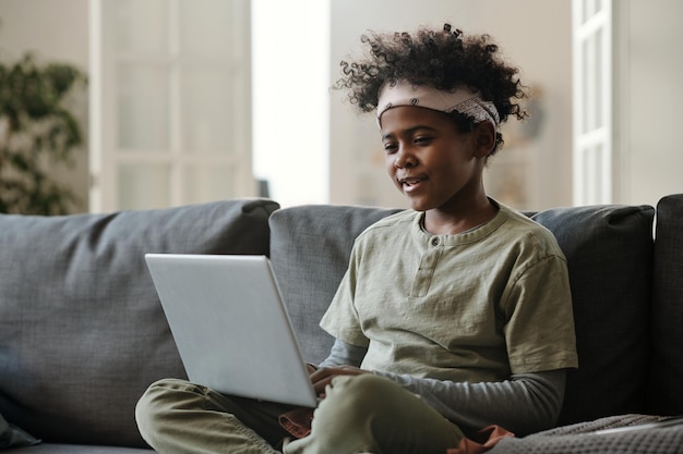 Garçon afro-américain en pyjama et bandeau assis sur le canapé