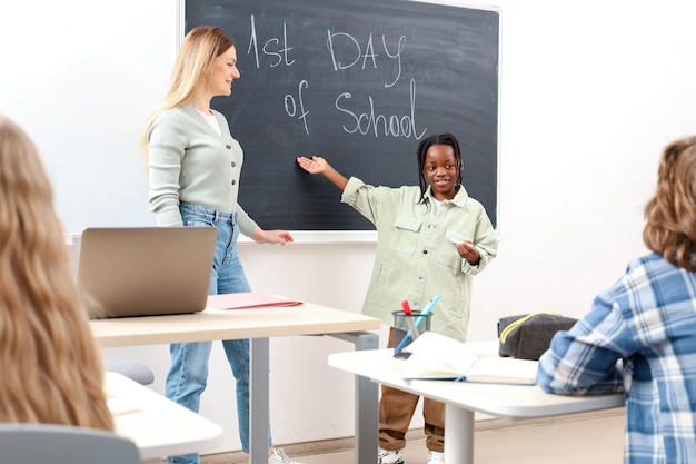 Photo un garçon afro-américain souriant montrant le premier jour d'école écrivant sur le tableau de bord retour à l'école