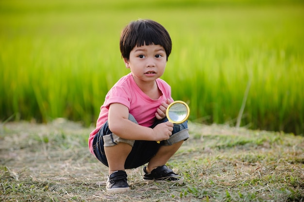 Le garçon d'âge préscolaire explore la nature avec la loupe