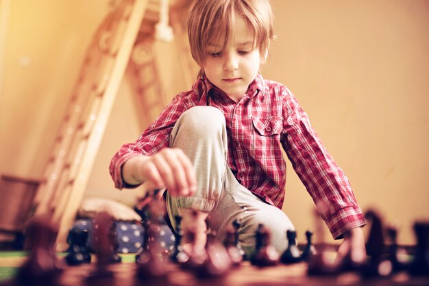 Garçon d'âge préscolaire mignon joue aux échecs à la maison