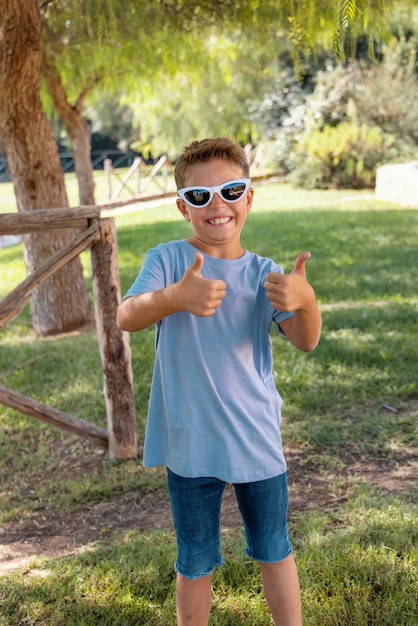 Photo un garçon d'âge préscolaire montre un signe de pouce levé dans un parc
