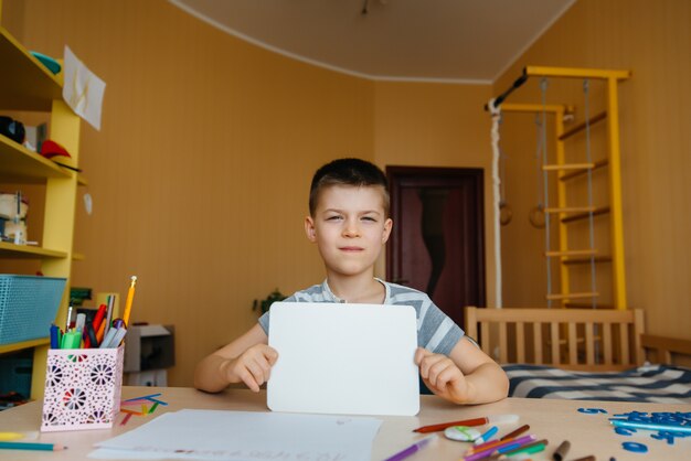 Un garçon d'âge scolaire fait ses devoirs à la maison. Formation à l'école