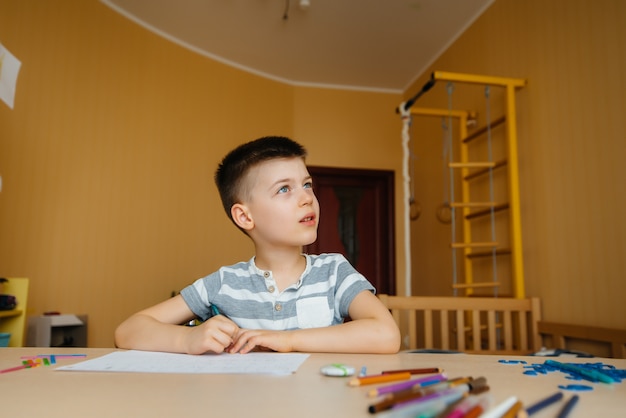 Un garçon d'âge scolaire fait ses devoirs à la maison. Formation à l'école.