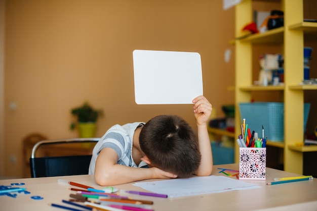 Un garçon d'âge scolaire fait ses devoirs à la maison. Formation à l'école.