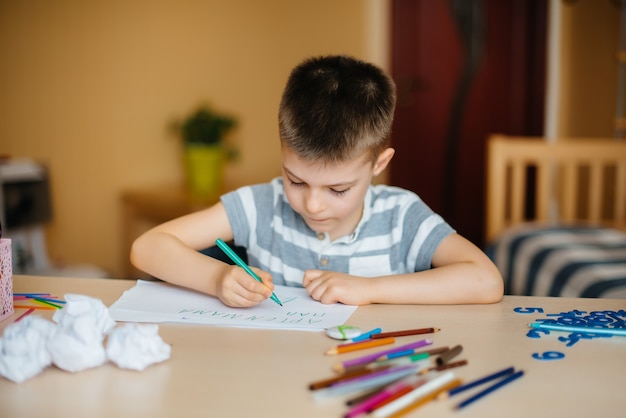 Un garçon d'âge scolaire fait ses devoirs à la maison