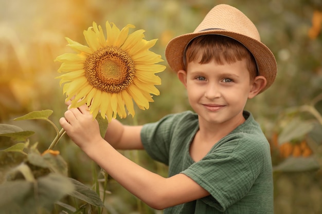 Photo un garçon d'âge scolaire se tient dans un champ avec des tournesols