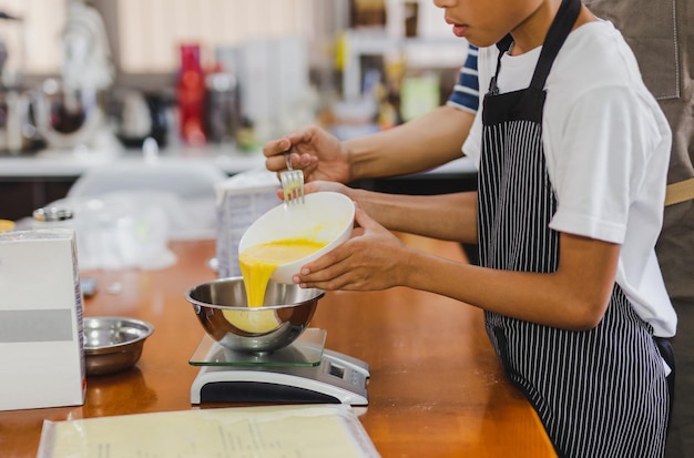 Garçon aidant maman à verser des jaunes d'œufs dans un bol pour la cuisson du gâteau