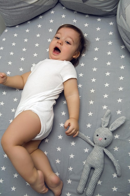 Photo un garçon de un an allongé dans un lit rond avec un jouet de lapin tricoté