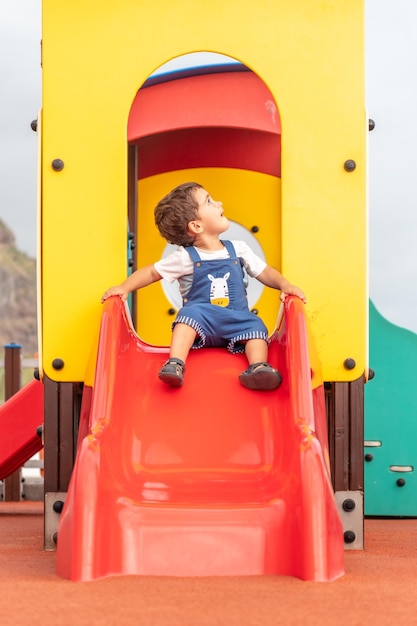 Garçon d'un an jouant dans une aire de jeux s'amusant dans un parc d'été adapté aux bébés