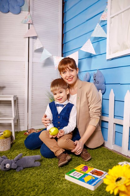 Garçon d'anniversaire embrassant sa jeune maman souriante après un événement drôle.