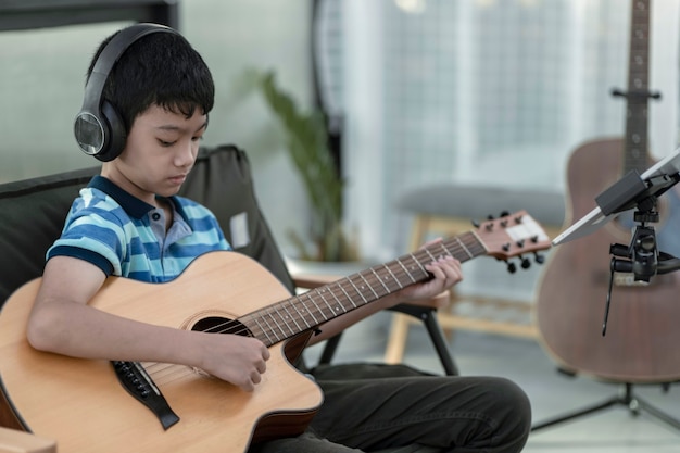 Un Garçon Apprenant à Jouer De La Guitare Concentration Sur La Musique