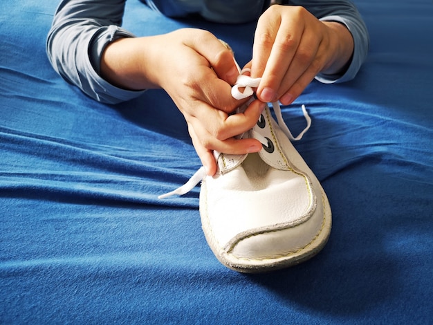 Un garçon apprend à nouer des lacets