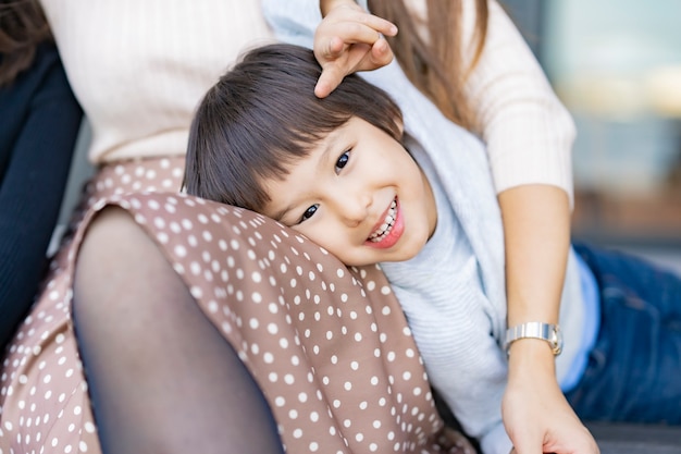 Un garçon appuyé contre sa maman et souriant