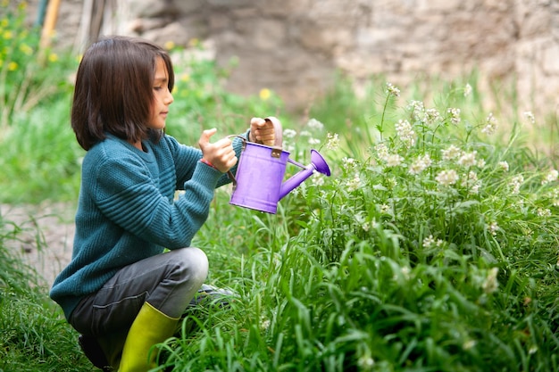 Garçon arrosant des plantes avec un arrosoir lilas