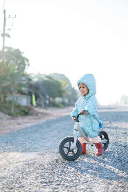 Un garçon asiatique âgé d&#39;environ 1 an et 11 mois avec une veste d&#39;hiver fait du vélo d&#39;équilibre pour bébé