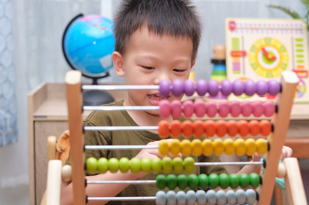 Garçon asiatique à l'aide de l'abaque avec des perles pour apprendre à compter