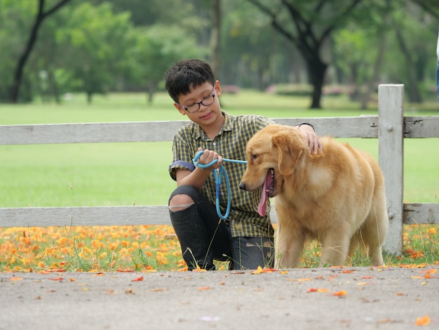 Garçon asiatique jouant avec chiot chien golden retrieiver dans le parc