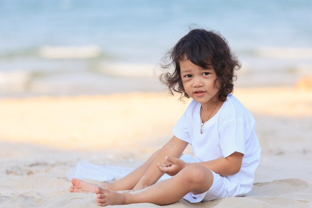 Un garçon asiatique joue sur la plage au soleil doré