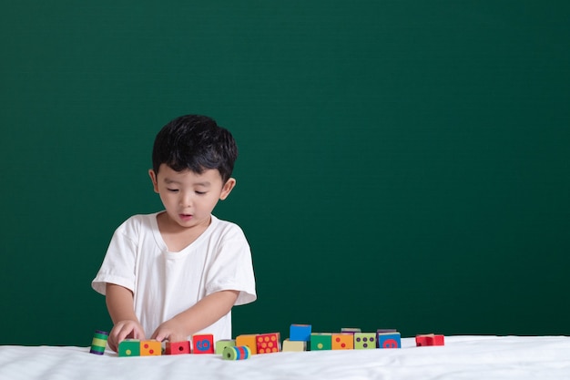 Garçon asiatique jouer jouet ou bloc carré puzzle sur tableau noir